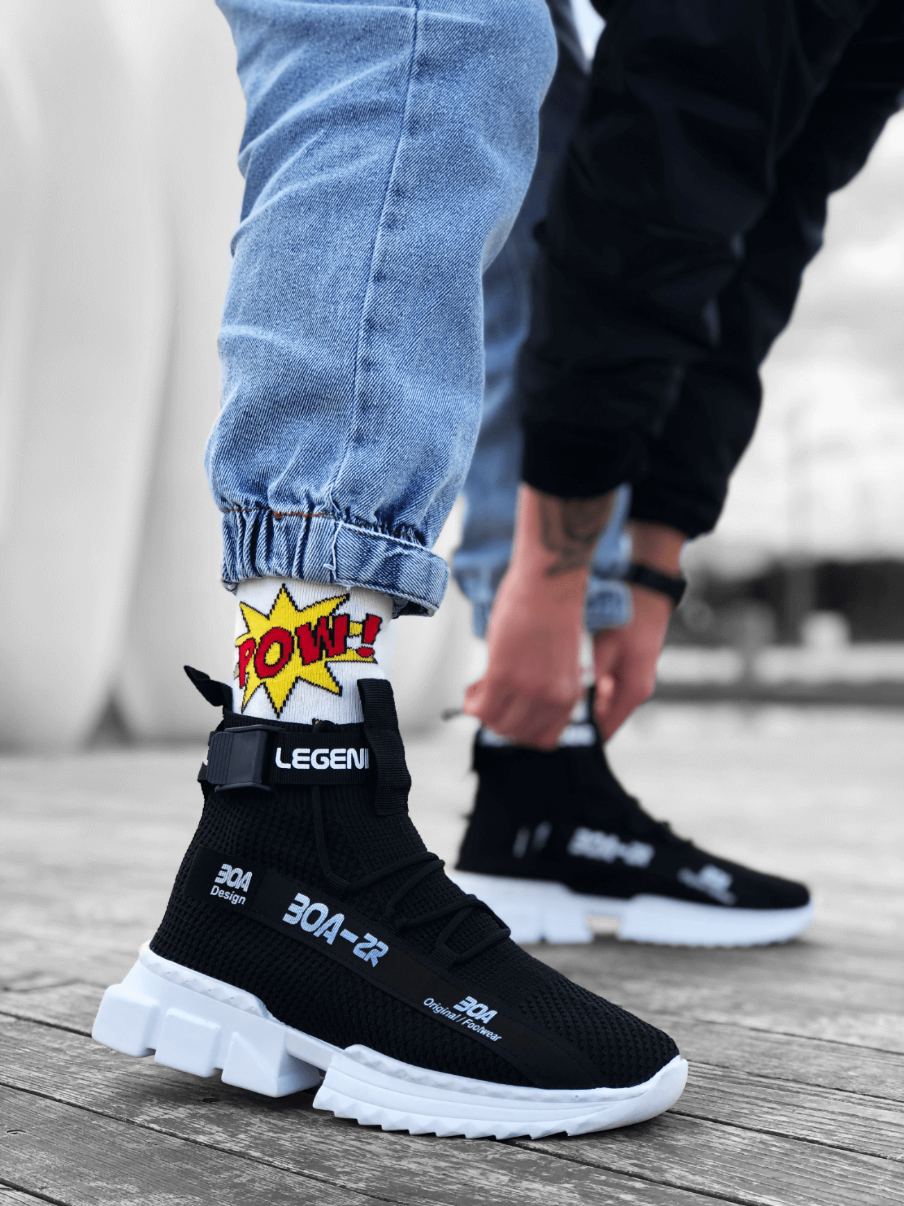 Black knit sneakers with white chunky sole and Velcro strap across the upper