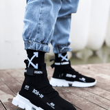 Black knit sneakers with white sole, hook-and-loop strap, and X-pattern detail