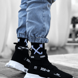 Black knit sneakers with white chunky sole and fabric pull tabs at heel