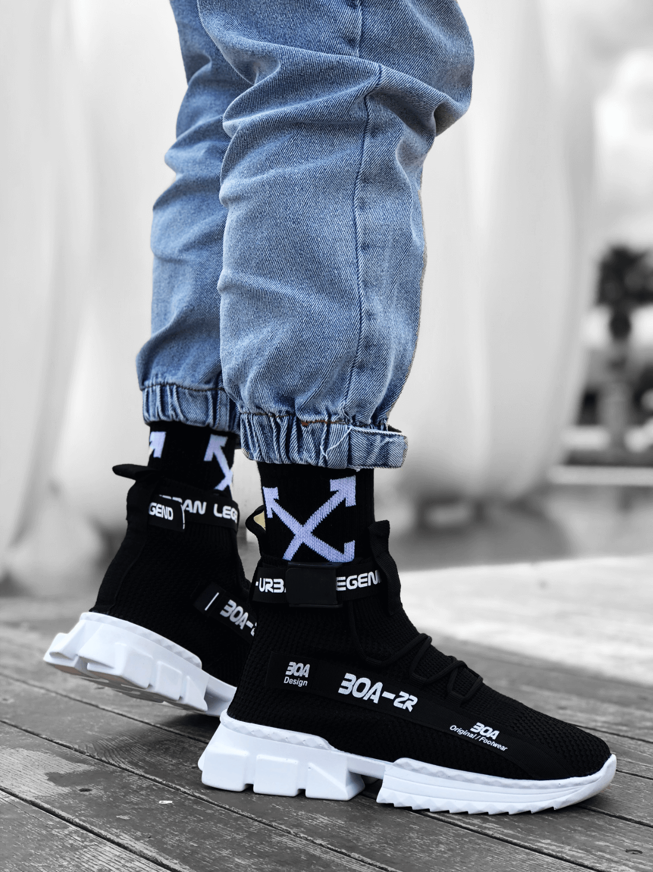 Black knit sneakers with white chunky sole and fabric pull tabs at heel