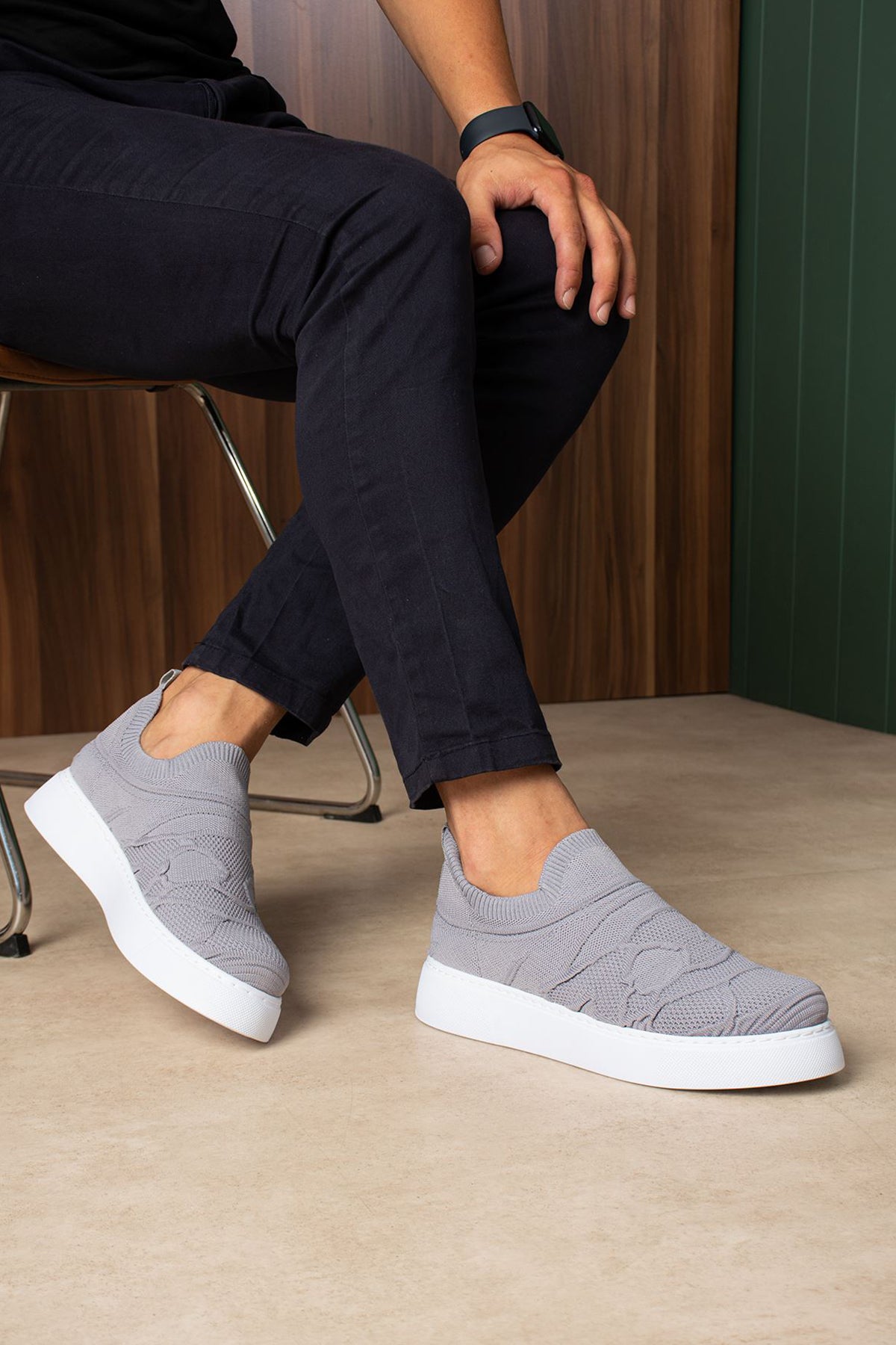 Gray knit sneakers with white sole, on feet seated, angled view