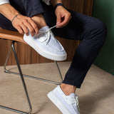 White and light blue lace-up knit sneakers on a seated person, side view.