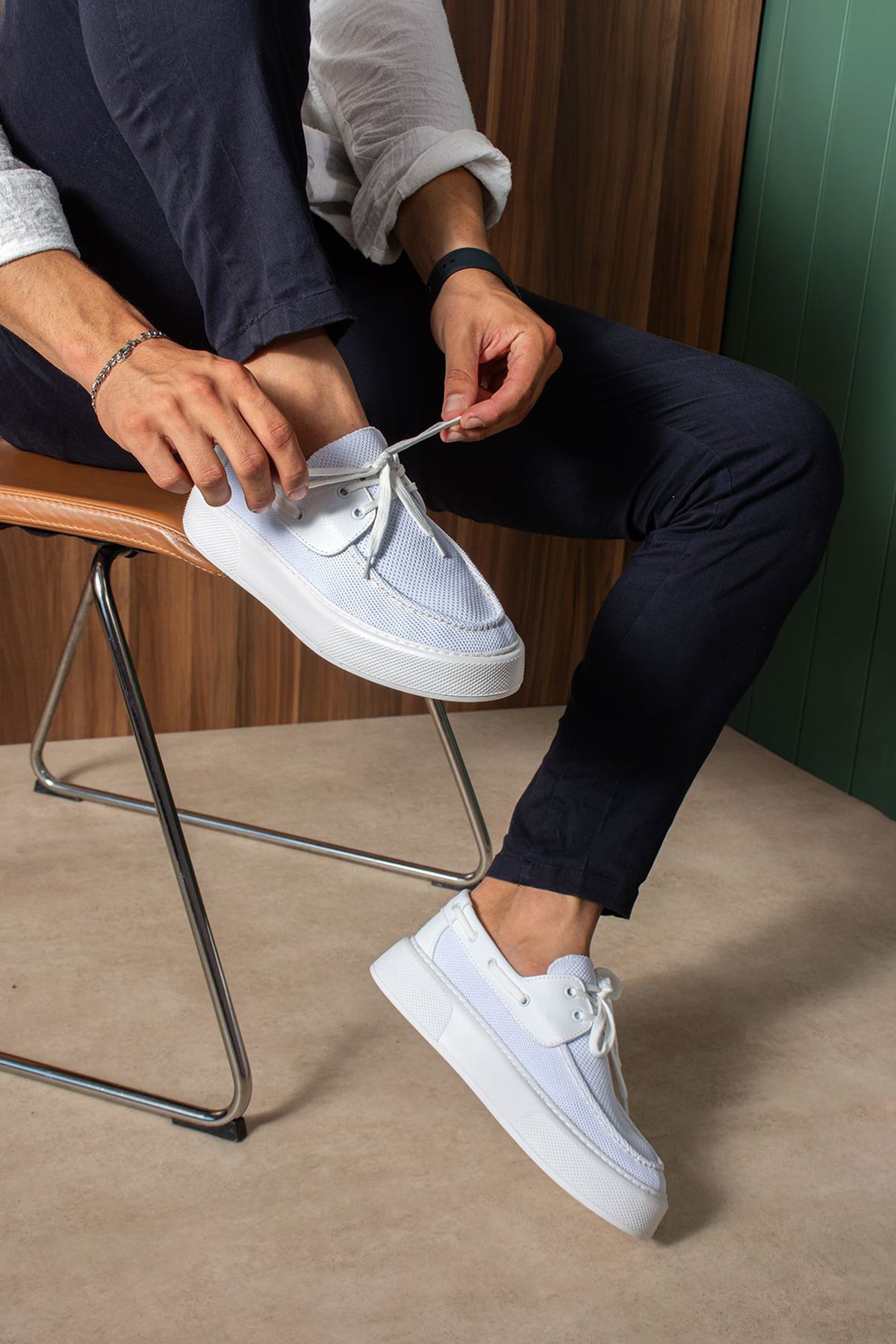 White and light blue lace-up knit sneakers on a seated person, side view.