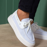 White and light blue lace-up knit sneakers, close-up side with eyelets and laces.