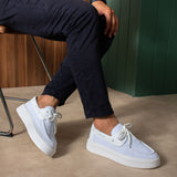 White and light blue lace-up knit sneakers, worn with dark pants, side view.
