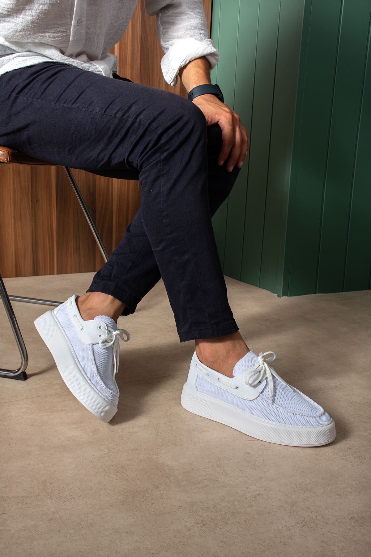White and light blue lace-up knit sneakers, worn with dark pants, side view.