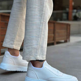 White knit low-top sneakers with textured upper and rubber sole, side view on foot