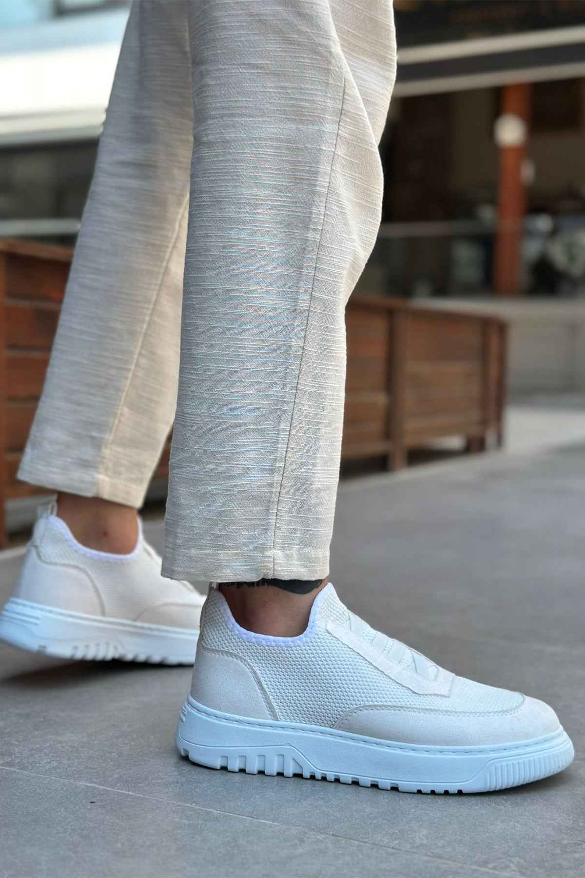 White knit low-top sneakers with textured upper and rubber sole, side view on foot