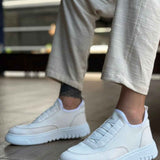White knit sneakers with velcro-style strap and treaded rubber sole, front side view