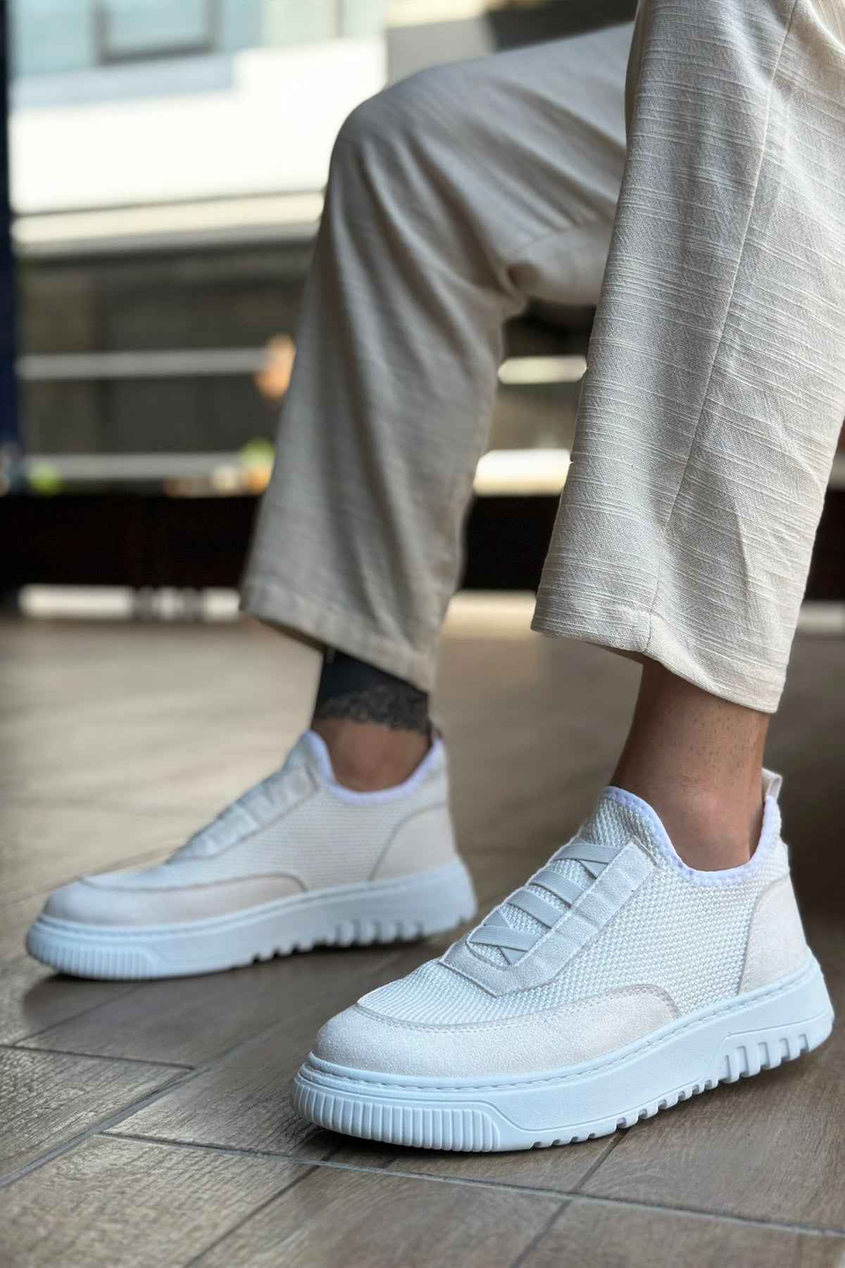 White knit sneakers with velcro-style strap and treaded rubber sole, front side view