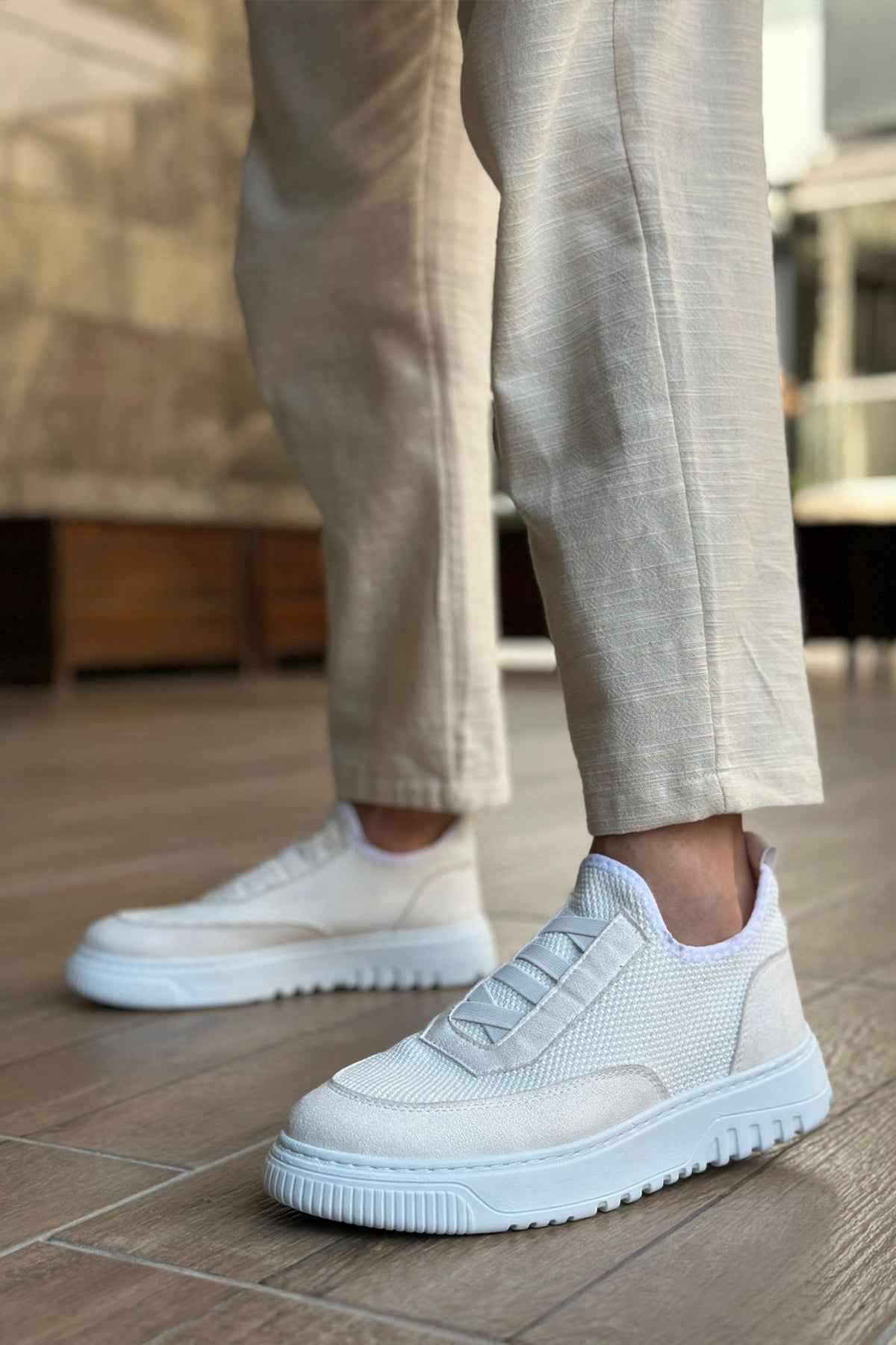 White knit sneakers with round toe and treaded rubber sole, stepping stance