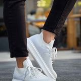 White knit sneakers with lace-up closure, textured upper, and flat rubber sole