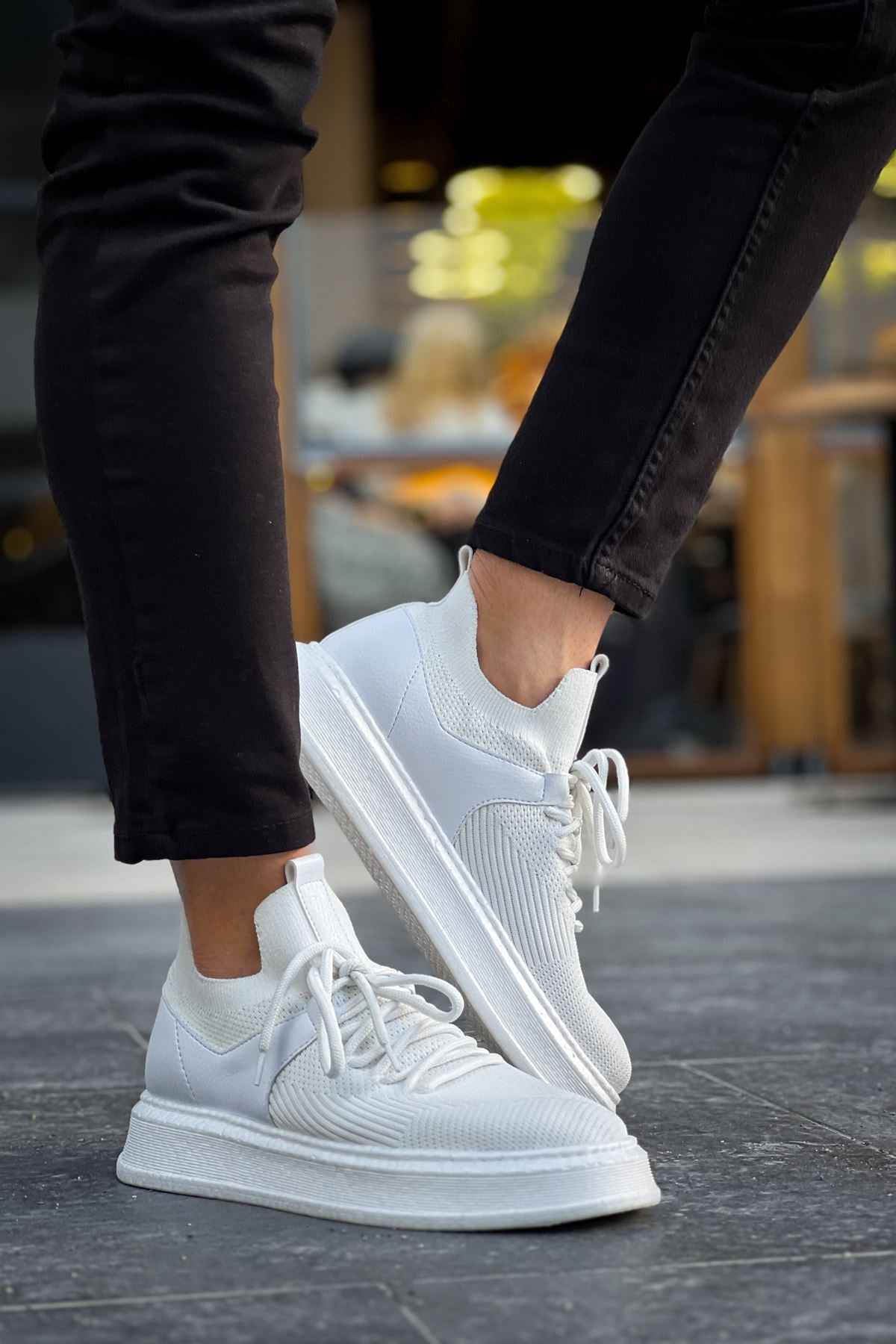 White knit sneakers with lace-up closure, textured upper, and flat rubber sole