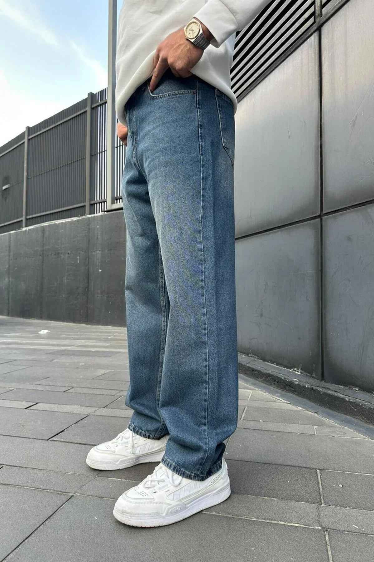 Relaxed blue denim jeans in side profile, wide legs and cuffed hems