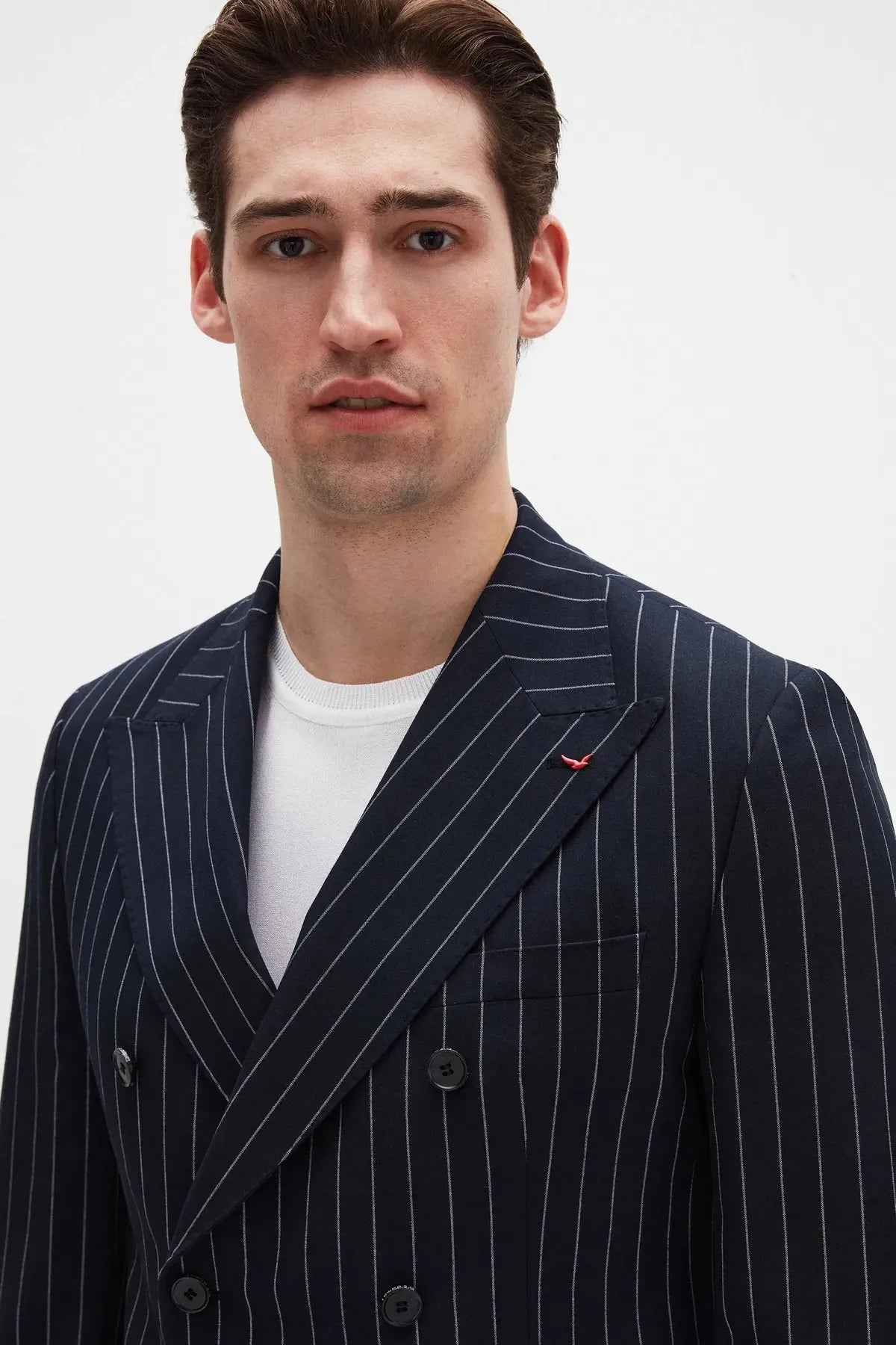 Men's navy pinstripe suit jacket with lapel detail and small chest pin