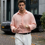 Mens pink button-up dress shirt with spread collar and long sleeves, paired with white trousers.