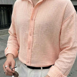 Mens pink dress shirt close-up with button placket and spread collar, long sleeves.