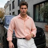 Mens pink dress shirt with button front and spread collar, long sleeves, with white trousers.