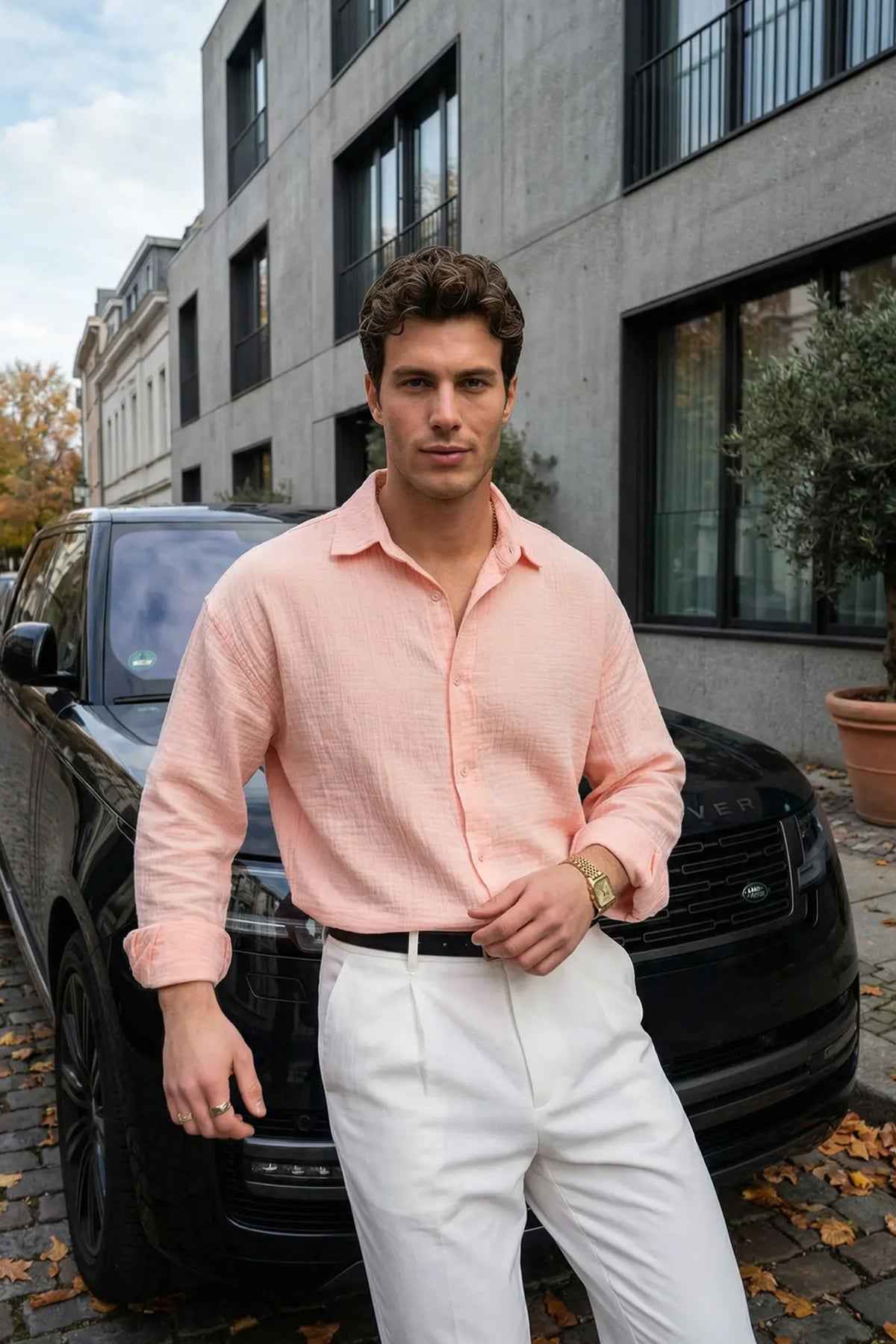 Mens pink dress shirt with button front and spread collar, long sleeves, with white trousers.
