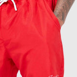 Red swim shorts with white drawstring, elastic waist, and small hem logo