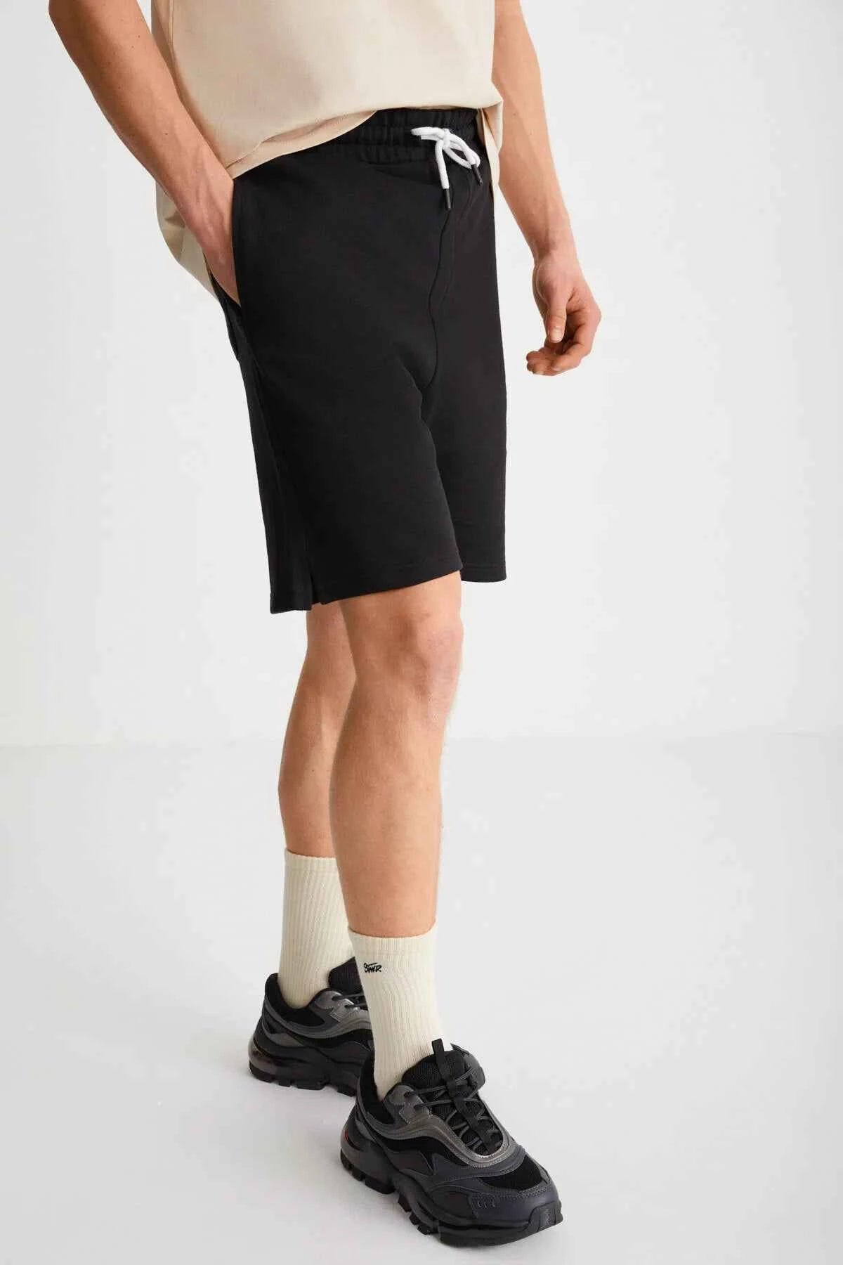 Black bermuda shorts with drawstring waist and above-knee hem