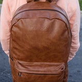 Tan leather backpack with top carry handle and stitched front zipper pocket