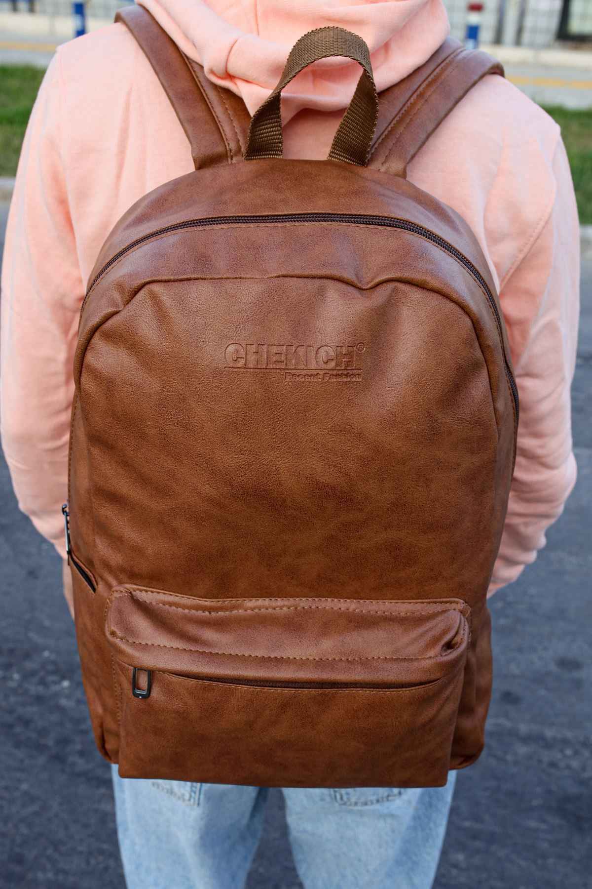 Tan leather backpack with top carry handle and stitched front zipper pocket