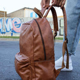Tan leather backpack with double side handles and front zipper closure