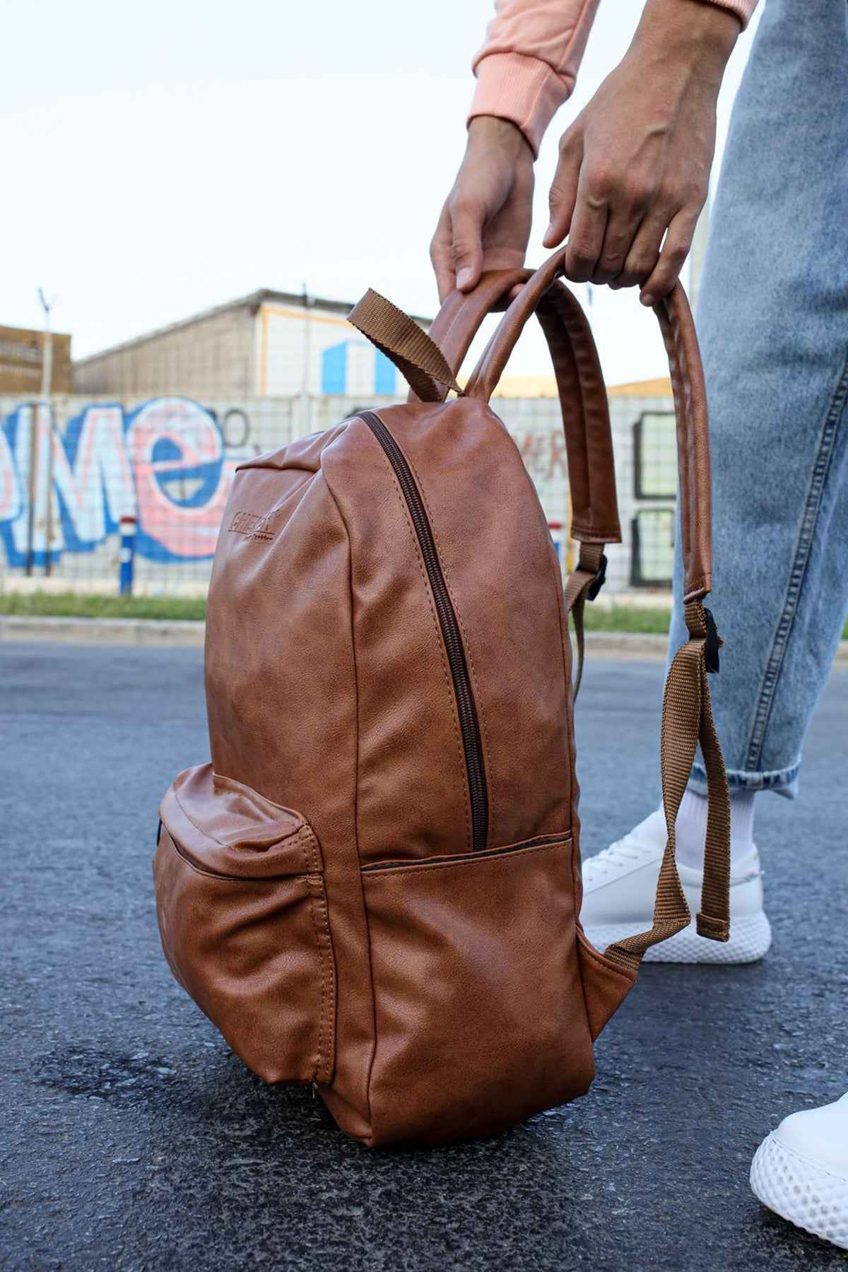 Tan leather backpack with double side handles and front zipper closure