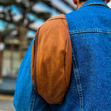 Tan leather crossbody bag side/back view with zip pocket on denim jacket
