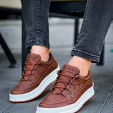Men's tan low-top sneakers on feet, white sole and laces