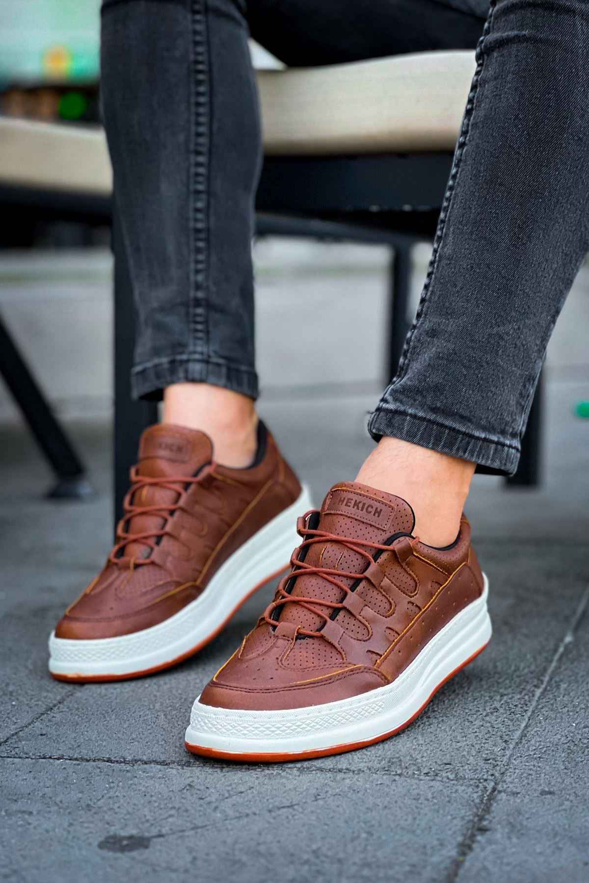 Men's tan low-top sneakers on feet, white sole and laces