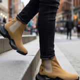 Tan suede ankle boots with side gore and black tread sole, worn with dark jeans.