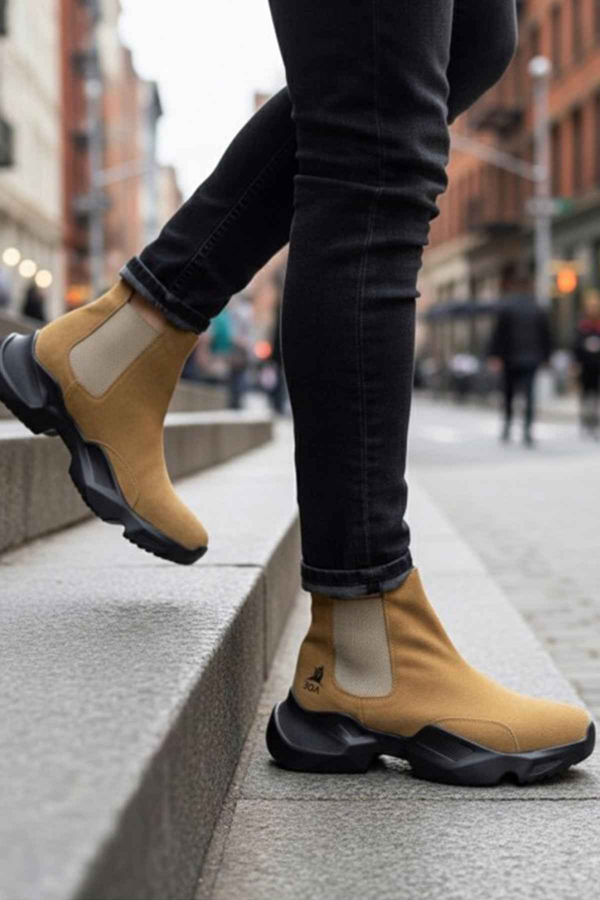 Tan suede ankle boots with side gore and black tread sole, worn with dark jeans.