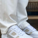 Men's white and beige lace-up sneakers with padded collar and gray rubber sole