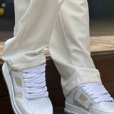 White and beige lace-up sneakers, front view with padded collar and tread sole