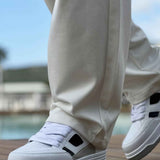 Men's white sneakers with black side strap and lace-up design
