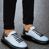 Men's two-tone sneakers on feet, white uppers with black stripes and thick black soles