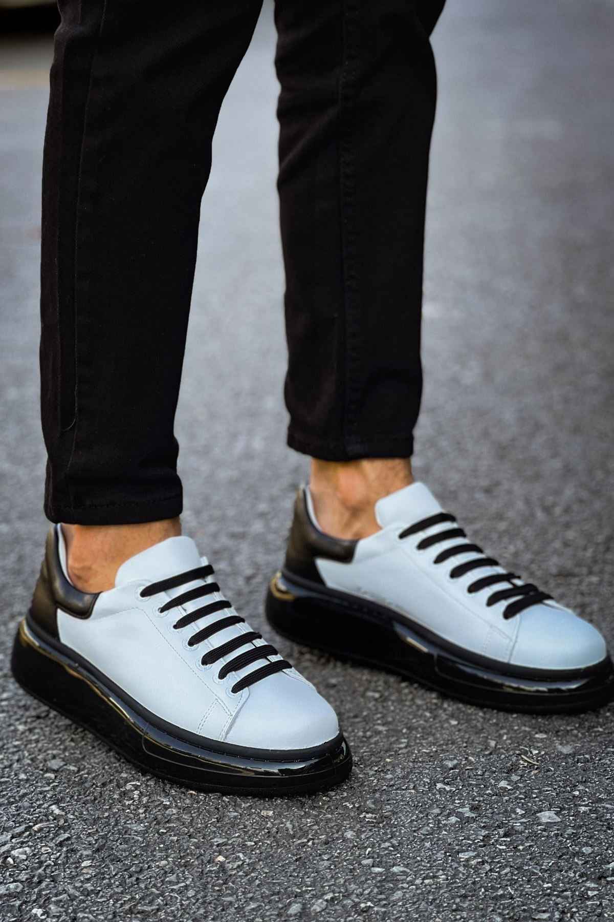 Men's two-tone sneakers on feet, white uppers with black stripes and thick black soles