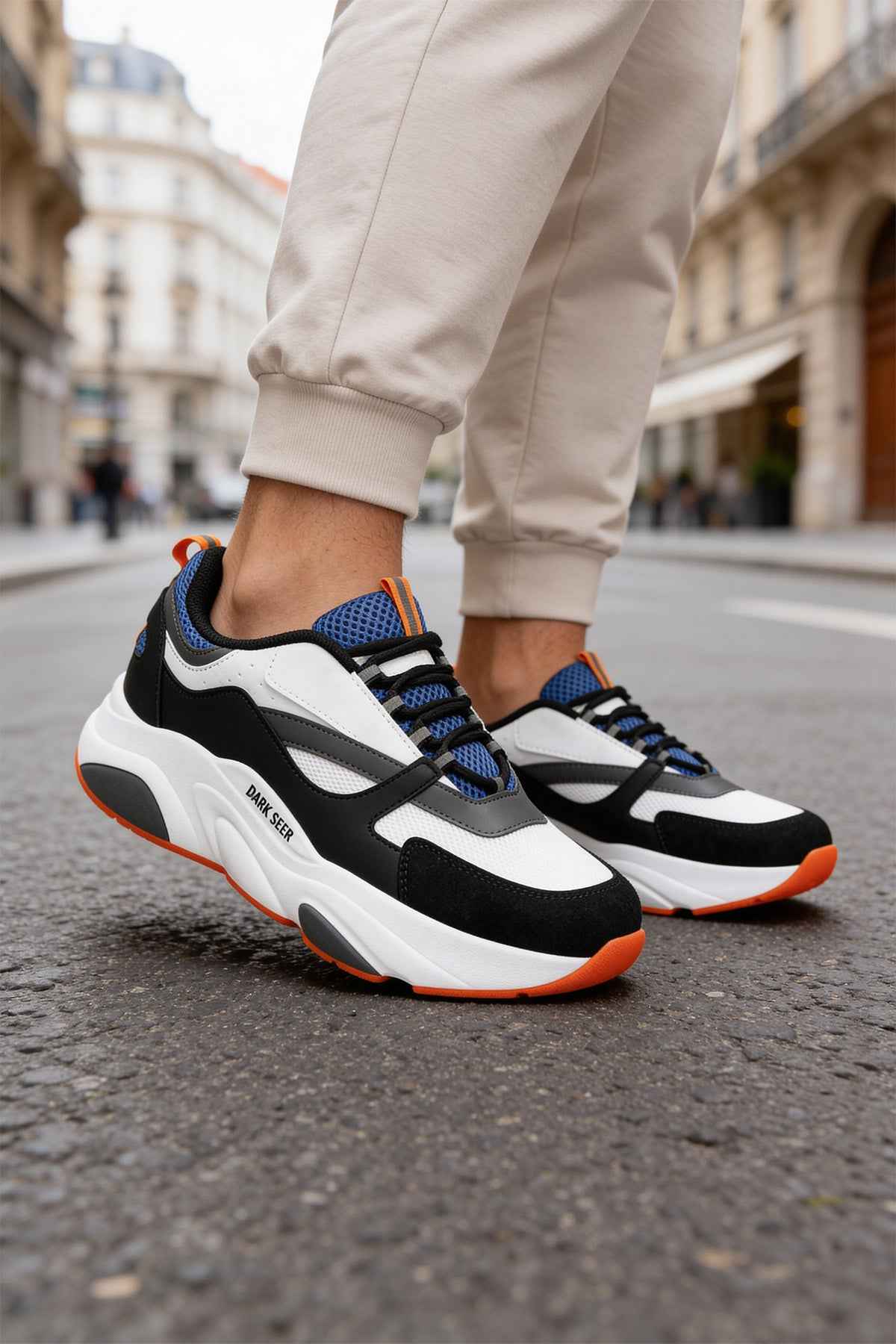 Men's lace-up sneakers, white and black uppers with blue panels; orange outsole.