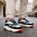 Men's lace-up sneakers, side view: white and black uppers with blue panels; orange soles.