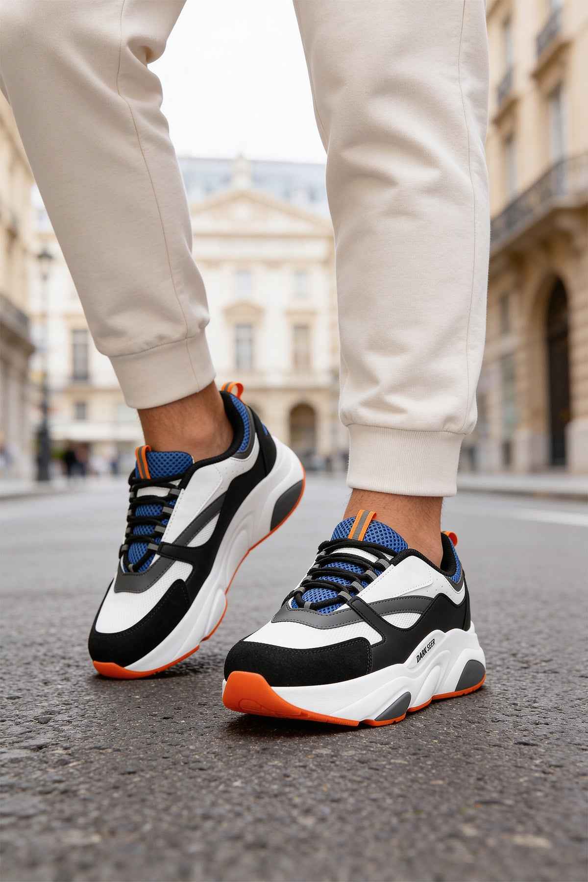 Men's lace-up sneakers, front/side view: white base, black swoosh, blue mesh, orange sole.