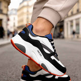Men's lace-up sneakers on foot: white, black, and blue upper with orange-trim outsole.