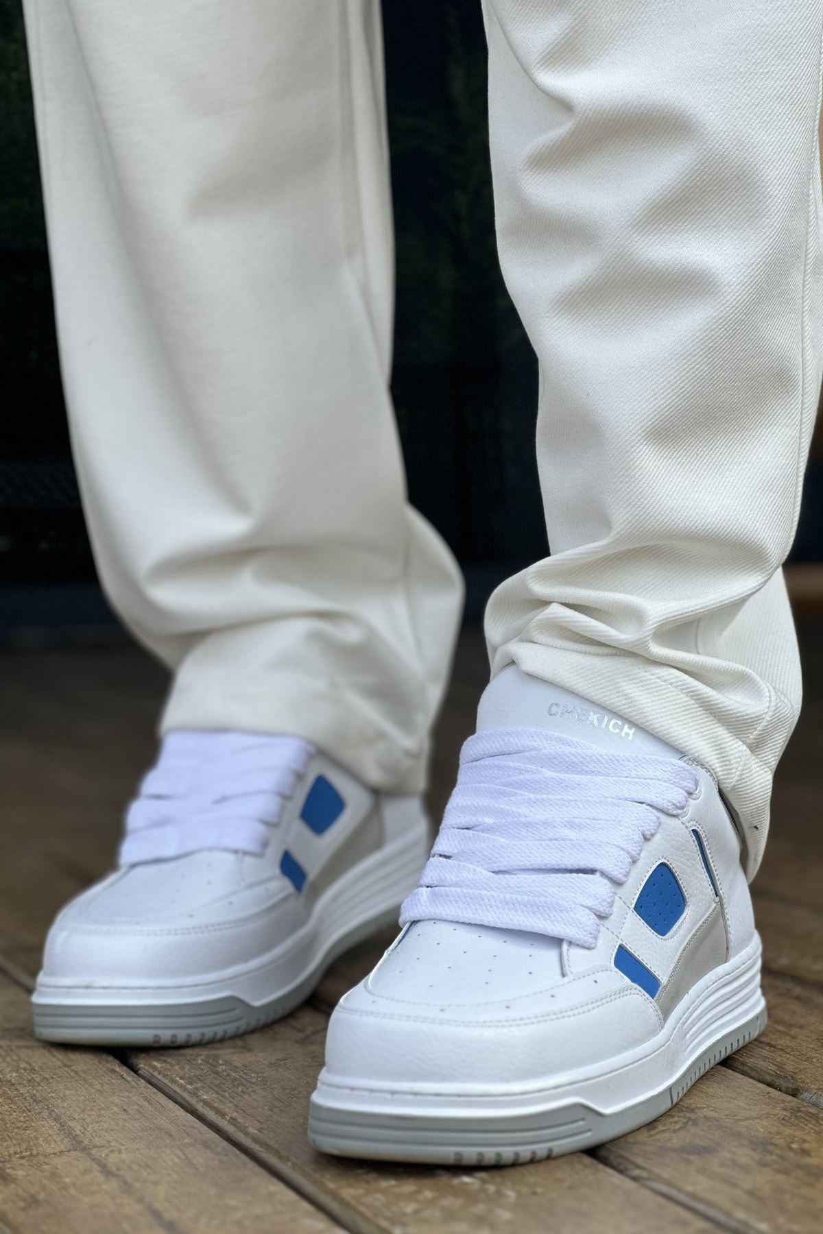 Men's white sneakers with blue strap accents and flat rubber sole