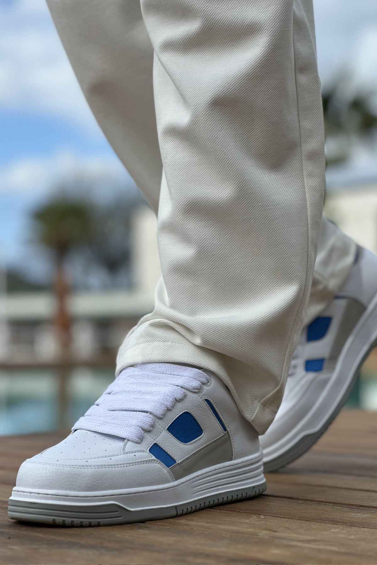 Men's white sneakers with blue side tabs and lace-up front