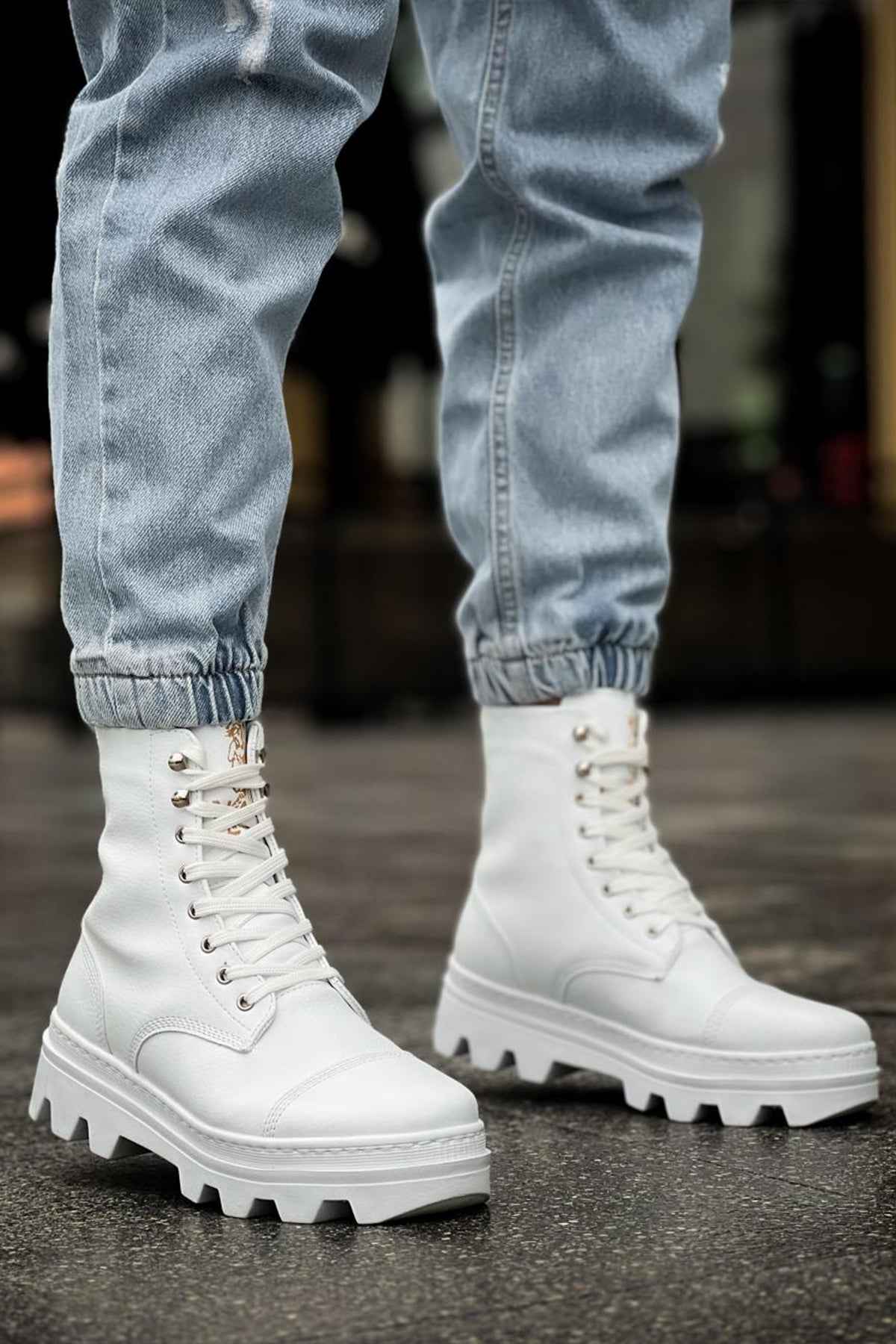 White lace-up boots with chunky tread sole and seam details, standing view