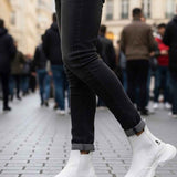 White ankle boots with thick tread sole and low shaft; dark jeans and socks visible