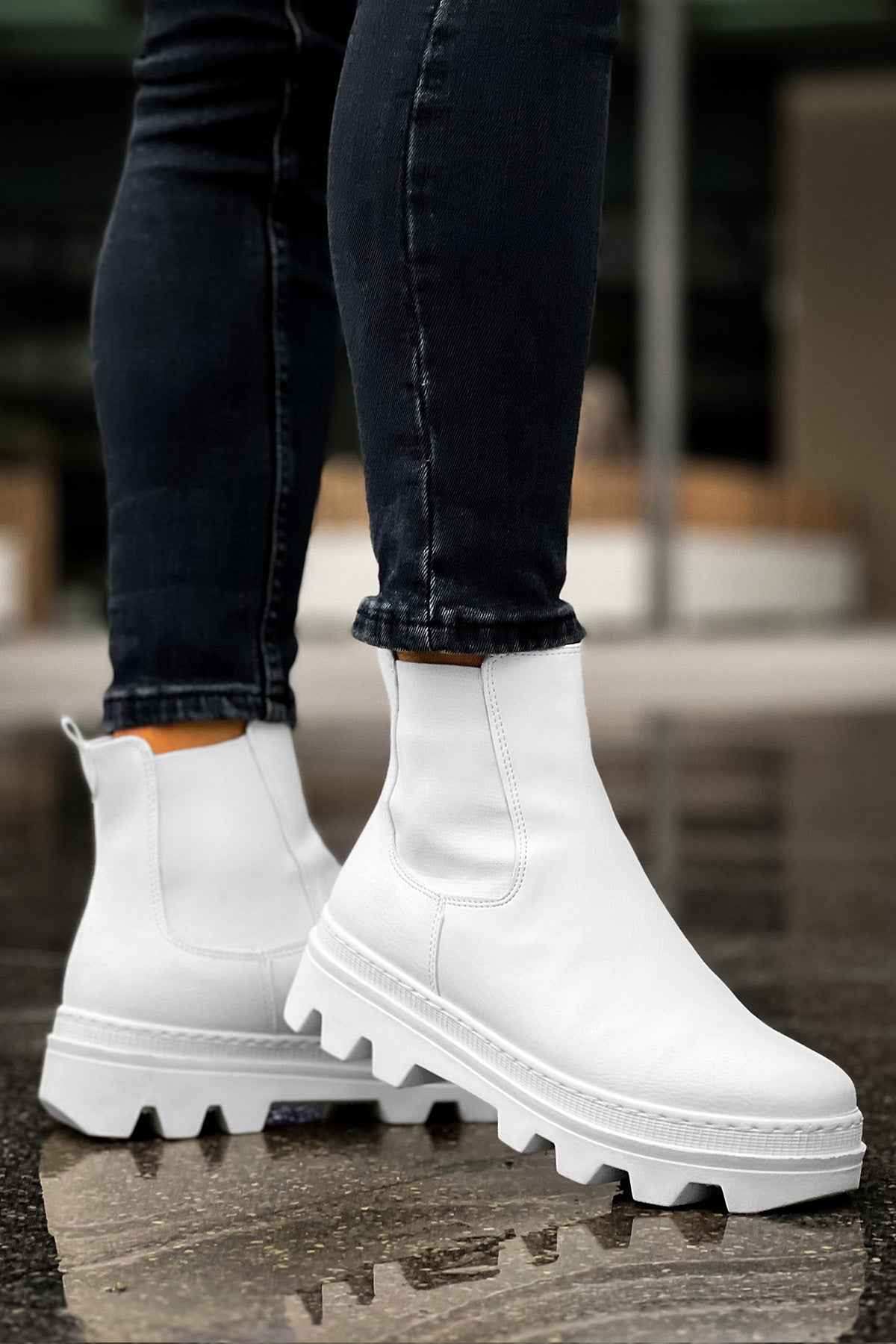 Men's white ankle boots with side elastic and lug sole, angled standing