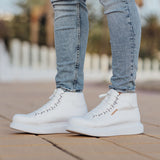 Pair of white lace-up boots standing on a paved walkway