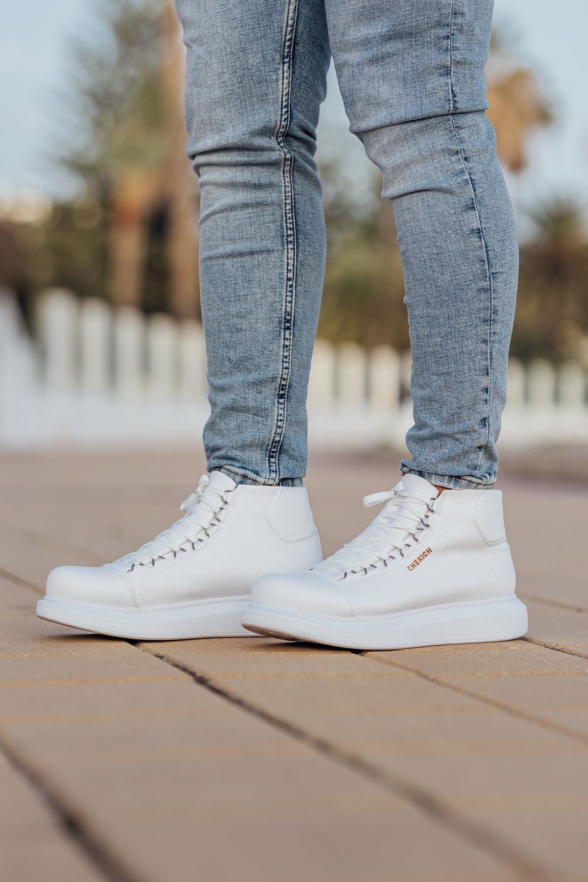 Pair of white lace-up boots standing on a paved walkway